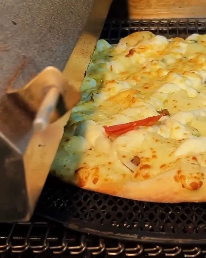 Pizza saindo do forno de esteira