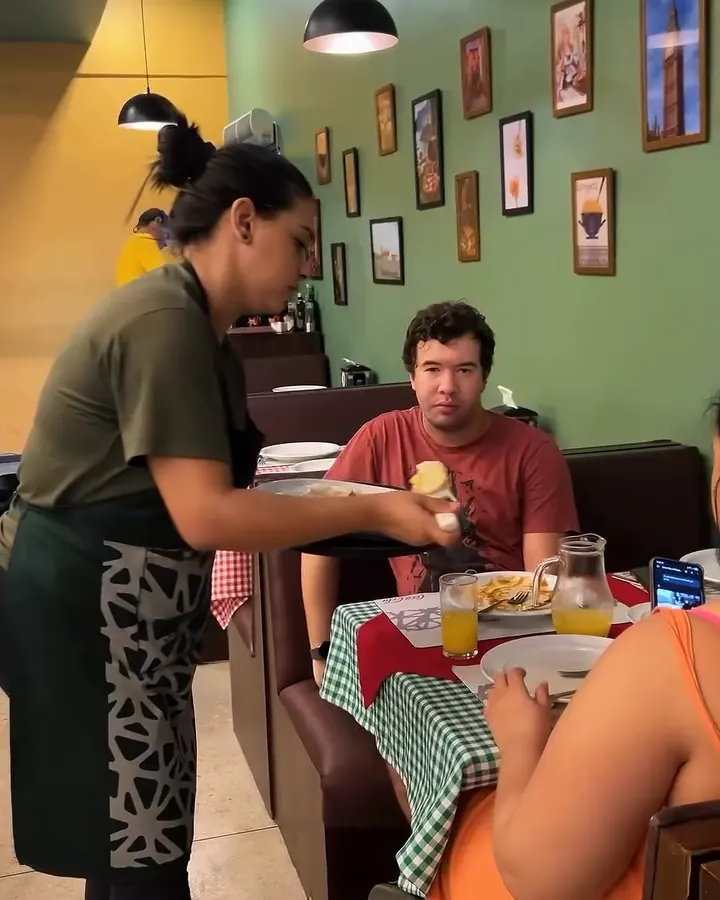 Garçonete servindo uma fatia de pizza à mesa